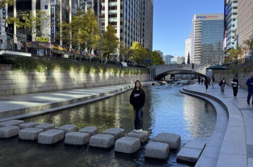 Marianna stojąca na przeskakowych kamieniach strumienia Cheonggyecheon w centrum Seulu