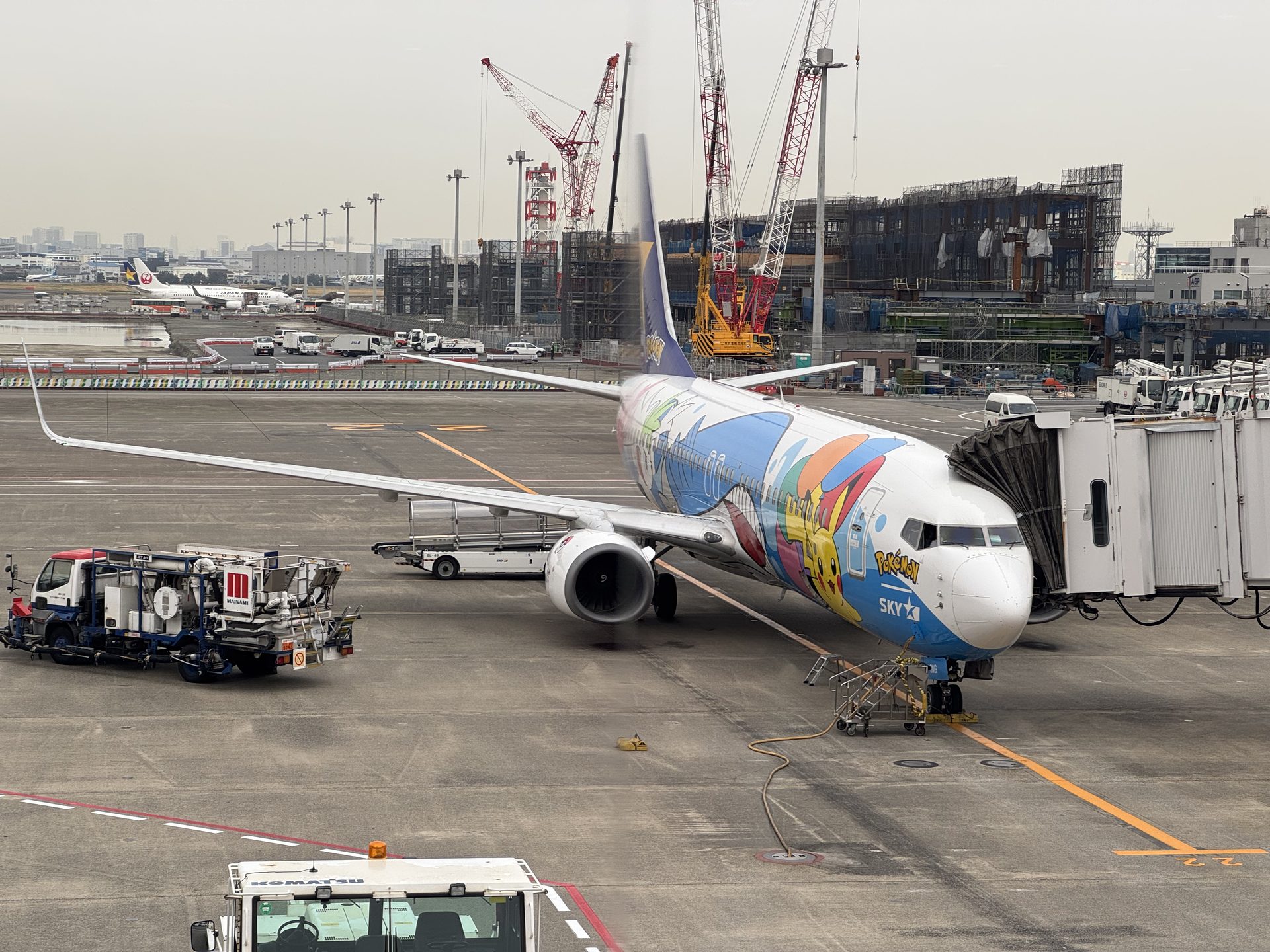 Boeing 737 linii Skymark Airlines w kolorowym malowaniu Pokémon przy bramce na lotnisku Haneda w Tokio