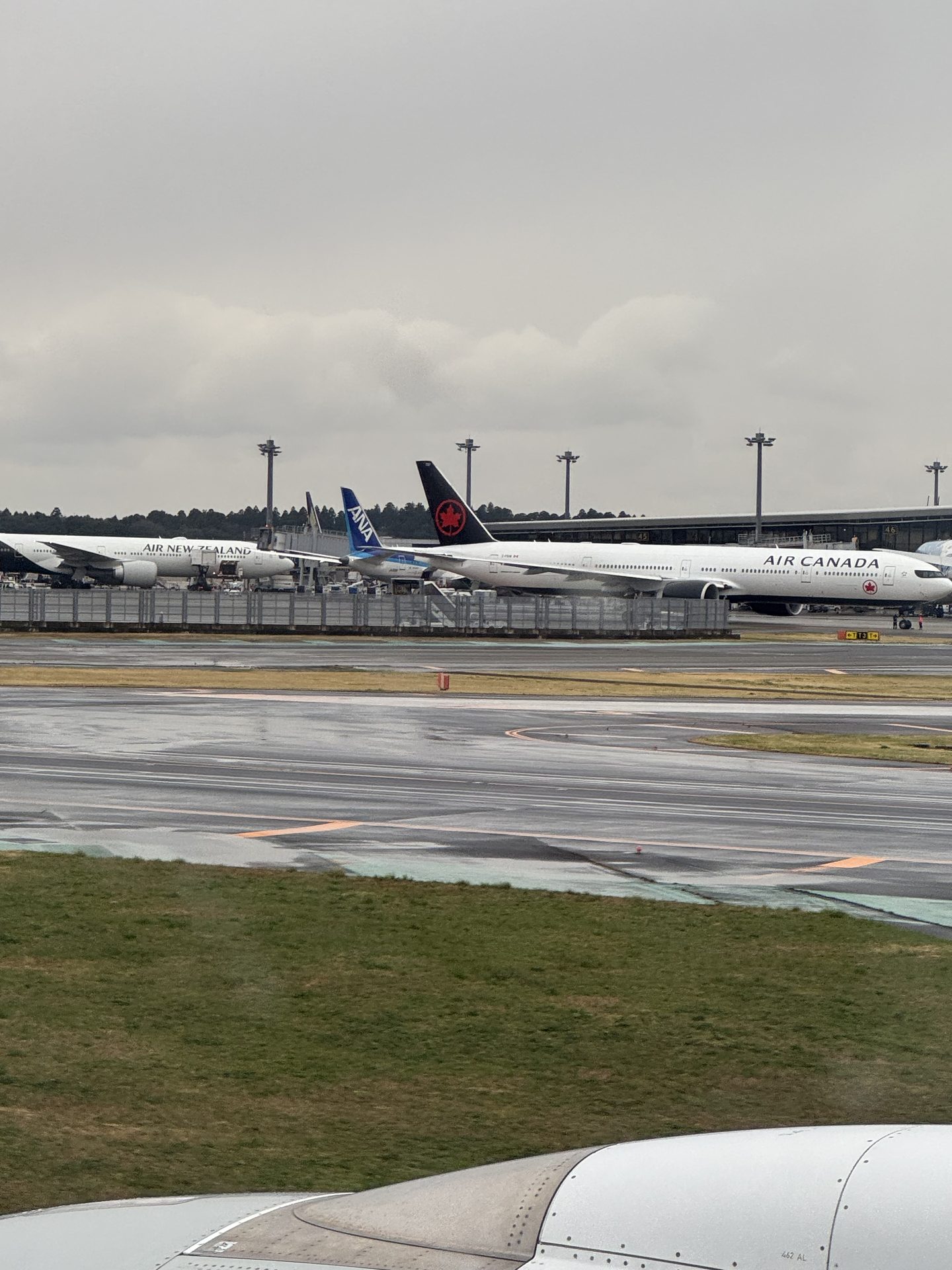 Boeing 777 Air Canada i samolot Air New Zealand widoczne razem na płycie lotniska Narita