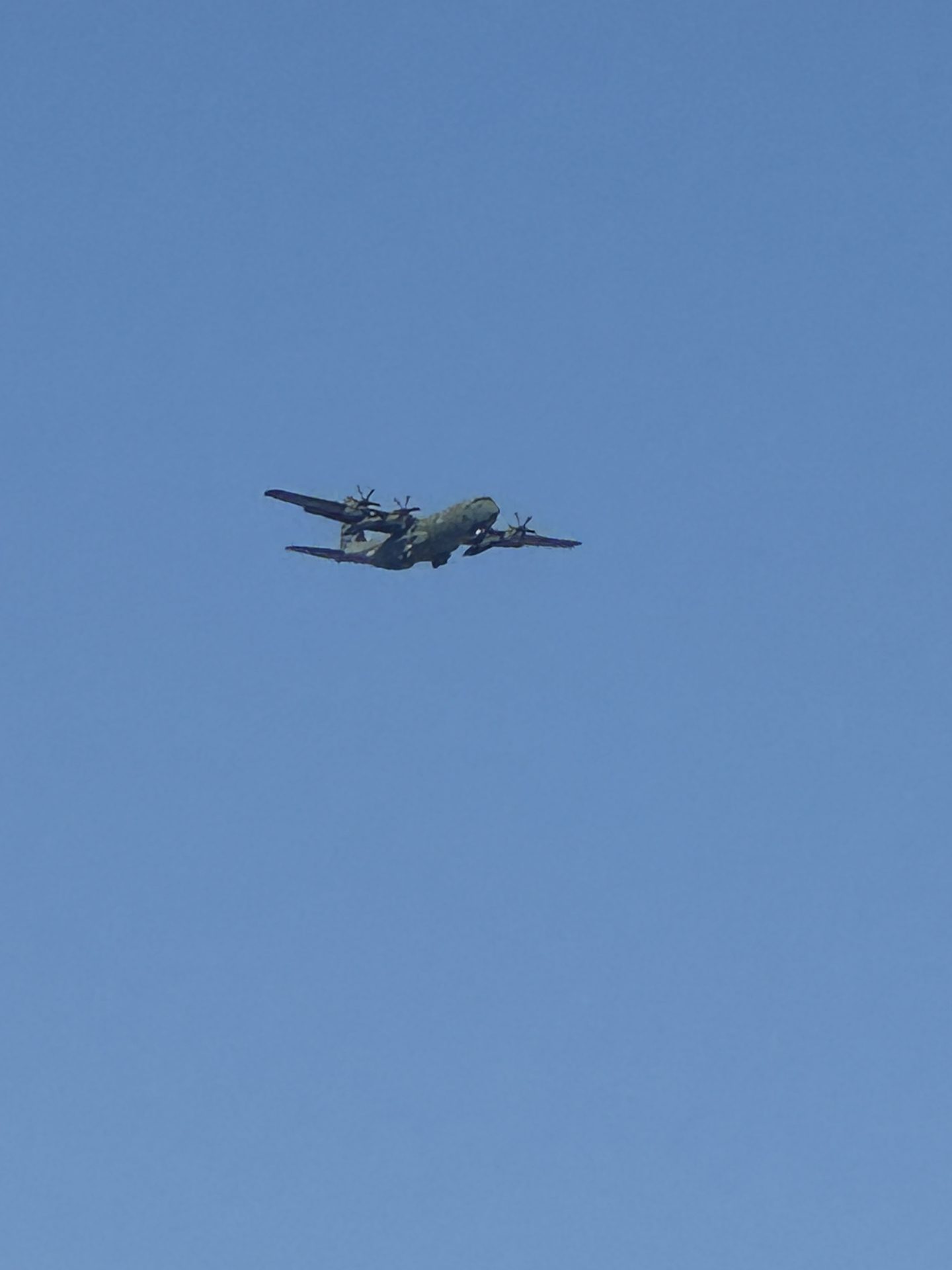 Wojskowy samolot transportowy Lockheed C-130 Hercules w kamuflażu lecący nad błękitnym niebem Seulu
