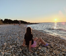 Marianna na kamienistej plaży Marianna siedząca na kamienistej plaży podczas zachodu słońca