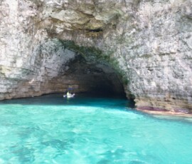Blue Grotto – wnętrze jaskini z łódką Łódka wpływająca do jaskini Blue Grotto z turkusową wodą