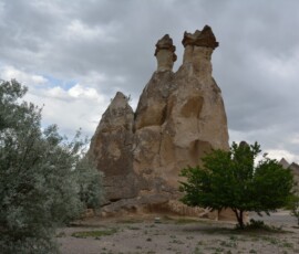 Göreme, Kapadocja. Kominy skalne – miliony lat erozji i mamy gotową rzeźbę. Dwa wysokie skalne kominy tufowe w Kapadocji na tle chmurnego nieba
