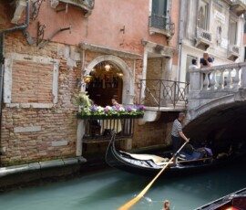 Gondolier w małym kanale Gondolier wiosłujący przez mały kanał obok kwiecistej kamienicy