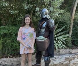 Marianna z Mandalorianem i Baby Yodą Marianna stojąca obok Mandaloriana trzymającego Baby Yodę w Galaxy's Edge