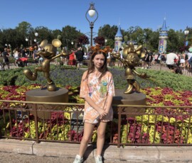 Marianna przy złotych figurach Mickey i Minnie Marianna stojąca pomiędzy złotymi figurami Myszki Miki i Myszki Minnie