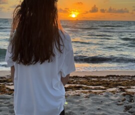 Marianna patrząca na wschód słońca nad oceanem Marianna stojąca tyłem na plaży i obserwująca wschód słońca nad Atlantykiem