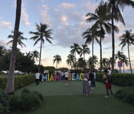 Napis Miami Beach wśród palm o zachodzie słońca Kolorowy napis Miami Beach otoczony palmami na tle różowego nieba