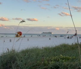 Siesta Key – biała plaża ze statkiem wycieczkowym Biała piaszczysta plaża Siesta Key z czerwoną wieżyczką ratowniczą i statkiem na horyzoncie