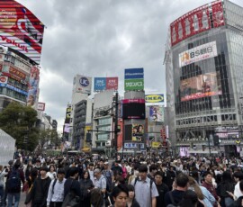 Skrzyżowanie Shibuya z poziomu chodnika Tłum na skrzyżowaniu Scramble Crossing w Shibuya z neontablic w tle
