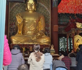 Świątynia Jogyesa – złoty Budda w Daewungjeon Wielki złoty posąg Buddy w głównej sali Daewungjeon świątyni Jogyesa podczas modłów