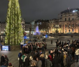 Trafalgar Square – chór śpiewający kolędy przy choince Chór w czapkach Mikołaja śpiewający kolędy przy choince norweskiej na Trafalgar Square nocą
