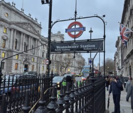 Westminster – wejście do stacji metra Żeliwne wejście do stacji metra Westminster Station z budynkami rządowymi w tle