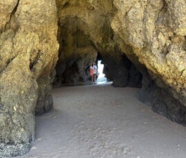 Grota w klifach Algarve Ciemna grota w złotych klifach Algarve z widokiem na plażę
