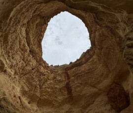Otwór w skale Algarve Widok przez okrągły otwór w klifie na niebo – Algarve