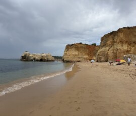 Plaża Algarve przy klifach Plaża Algarve z klifami i spokojnym morzem przy pochmurnym niebie