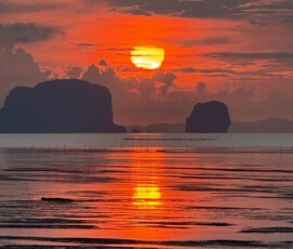 Krabi – spektakularny czerwony zachód słońca nad skałami Płonące niebo o zachodzie słońca z sylwetkami skał karst odbijającymi się w morzu
