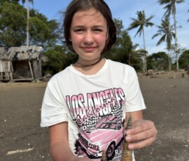 Marianna trzyma muszelkę na tropikalnej plaży Marianna prezentuje dużą muszelkę znalezioną na dzikiej plaży w Tajlandii
