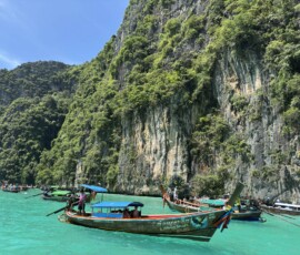 Phi Phi – Pileh Lagoon – łódka przy ścianie skalnej Kolorowa łódka longtail przy stromej ścianie skalnej pokrytej zielenią w lagunie Pileh