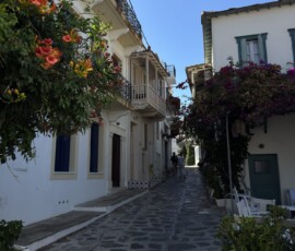 Kwiecista uliczka – Skopelos Chora Wąska brukowana uliczka z bougainvilleą i kwiatami w Chorze na wyspie Skopelos