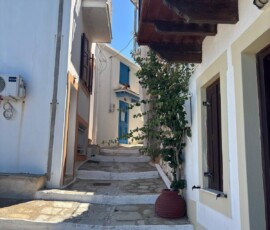 Wąska uliczka ze schodami – Skopelos Chora Wąska uliczka z kamiennymi schodami i niebieską bramą w Chorze na Skopelos