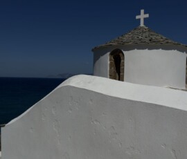 Kaplica na skale nad morzem – Skopelos Biała kaplica z kamiennym dachem na skale na tle Morza Egejskiego na Skopelos