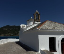 Kościółek z dzwonnicą nad morzem – Skopelos Biały kościółek z kamienną dzwonnicą na skale nad Morzem Egejskim na Skopelos