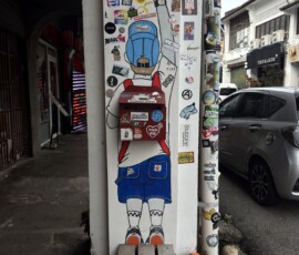 Sztuka uliczna w George Town Słup oklejony naklejkami i figurką w George Town w Penang