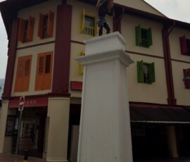 Rzeźba tragarza w Chinatown Brązowa rzeźba tragarza na cokole przed kolorową kamienicą w Chinatown